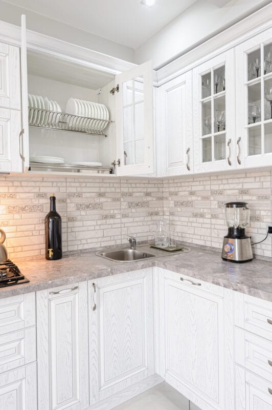 Modern white kitchen with open cabinets and blender.